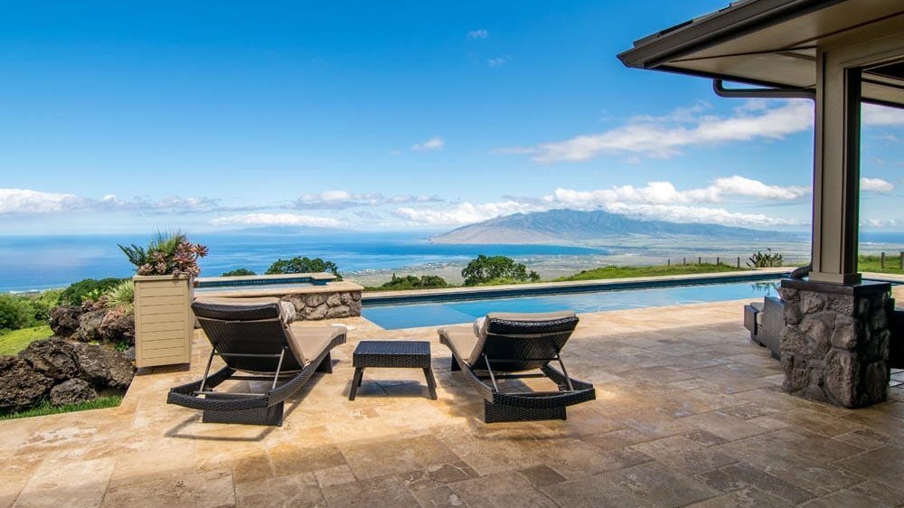 Infinity-edge pool and terrace at Keokea Ranch Estate looking out over the Pacific and the West Maui Mountains at golden hour